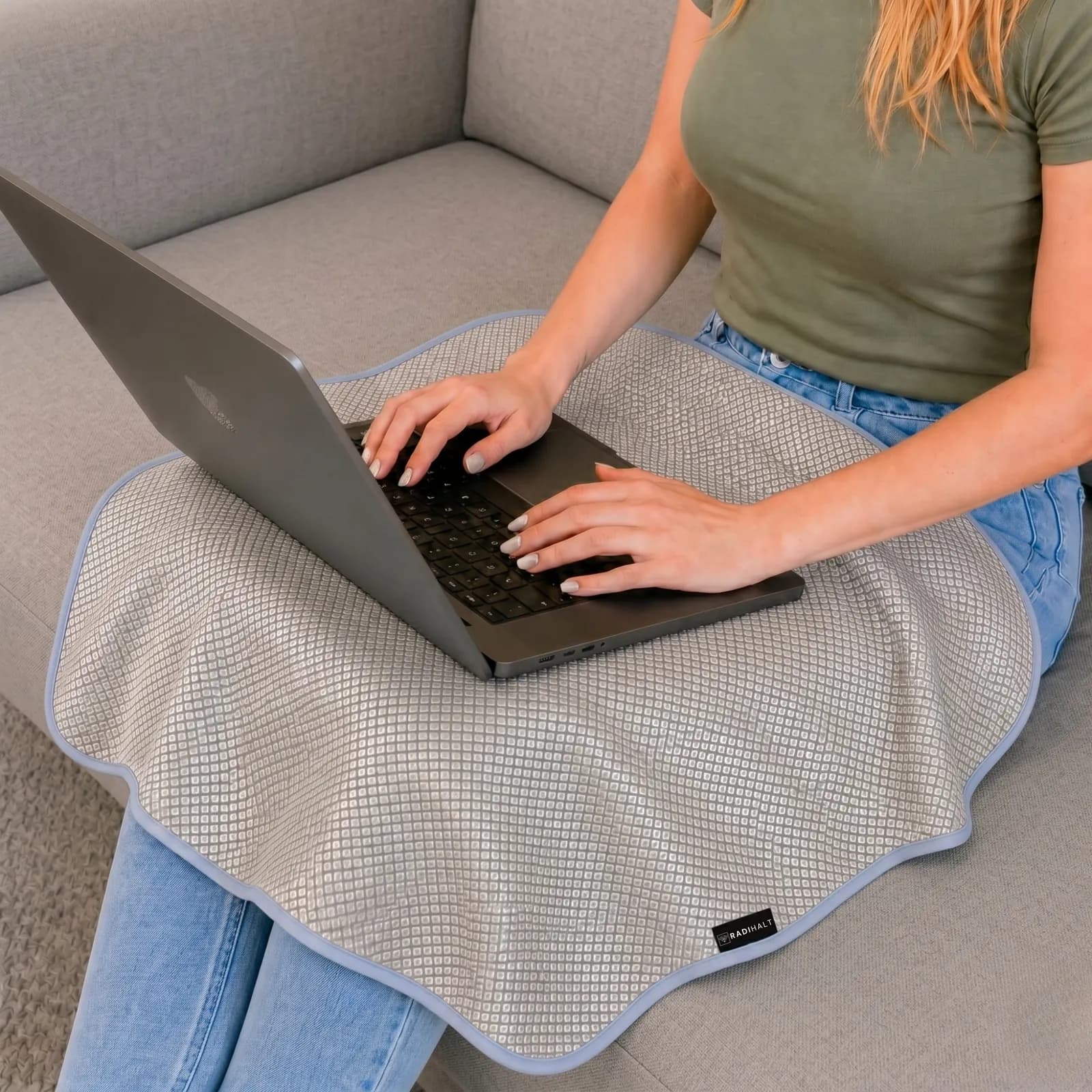 Laptop on a lap over a RADIHALT blanket with its copper-nickel side facing up